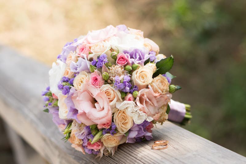 H? rliga vigselringar med buketten av blommor F? rklaring av f? r? lskelse, v? r fotografering för bildbyråer