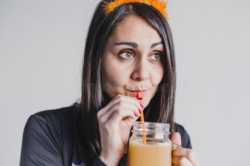 H? rligt dricka orange kvinnabarn f? r fruktsaft. Med ett svart och vitt skelett. f? r den grymma s? ger miniatyrreaperen halloween f? royaltyfri fotografi