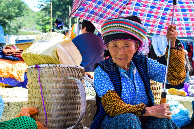 Ha GIANG, VIETNAM - November 08, 2015: Niet geïdentificeerde Hmong-vrouw die haar baby op rug houden terwijl het lopen naar huis stock afbeelding Ha GIANG, VIETNAM - November 08, 2015: Niet geïdentificeerde Hmong-vrouw die haar baby op rug houden terwijl het lopen naar huis stock afbeelding