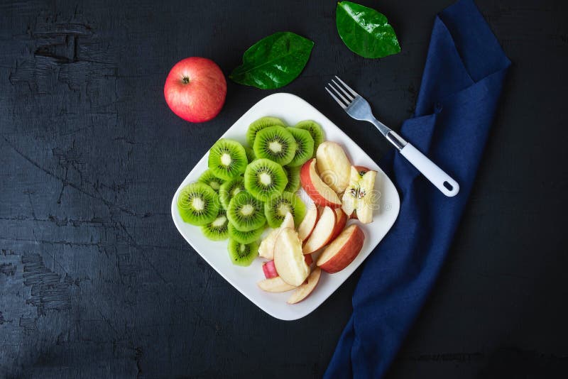 Ha mescolato il kiwi e le mele freschi della frutta con l'uva in un piatto su una tavola di legno immagine stock Ha mescolato il kiwi e le mele freschi della frutta con l'uva in un piatto su una tavola di legno immagine stock