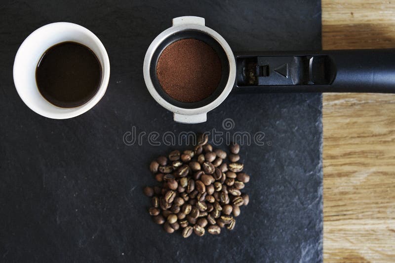 Habas y café puesto a tierra en tenedor del filtro en tablero negro del stoun desde arriba fotografía de archivo Habas y café puesto a tierra en tenedor del filtro en tablero negro del stoun desde arriba fotografía de archivo