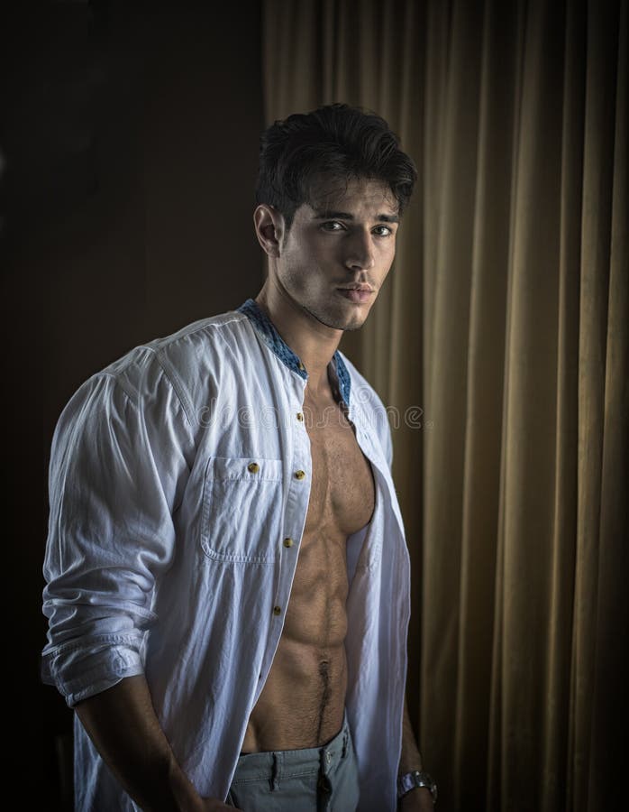 Habillage sexy de jeune homme par des rideaux en fen?tre image stock Habillage sexy de jeune homme par des rideaux en fen?tre image stock
