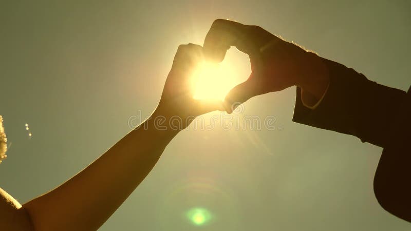 Hacer de la forma de un corazón con los dedos un símbolo de amor y vida. sol en mano. silueta de una pareja amorosa haciendo el co