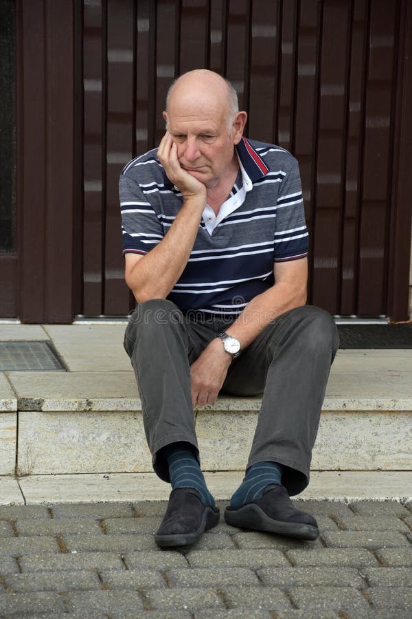 Hacia fuera hombre mayor bloqueado que se sienta delante de su casa foto de archivo libre de regalías Hacia fuera hombre mayor bloqueado que se sienta delante de su casa foto de archivo libre de regalías