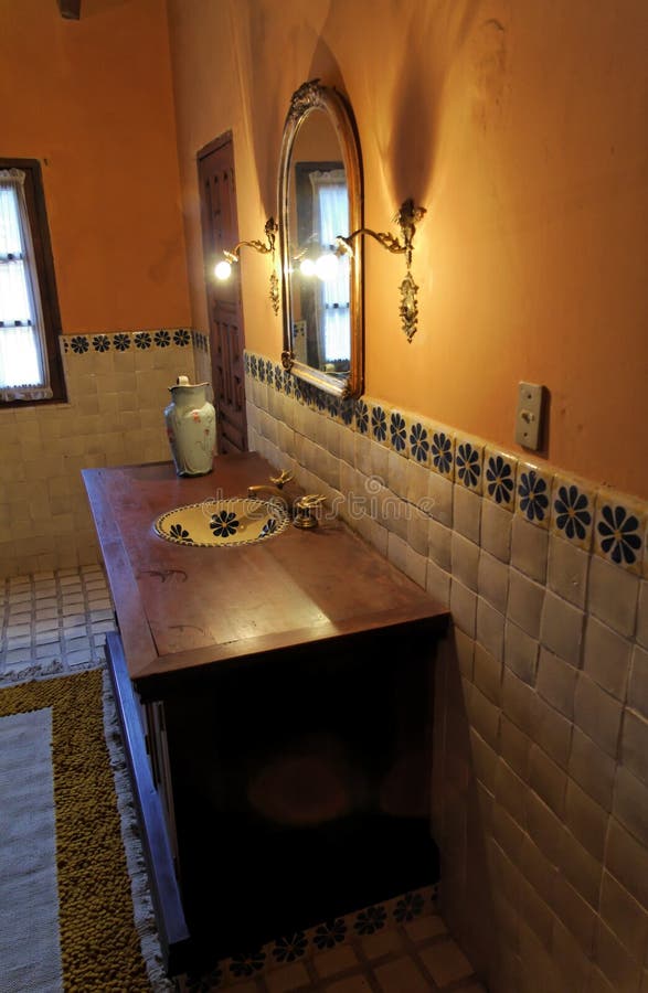 A typical colonial bathroom in an old hacienda in Guanajuato, mexican colonial heartland. The image shows the blue flower tiles, a lamp, a vase and a mirror inside the bathroom. A typical colonial bathroom in an old hacienda in Guanajuato, mexican colonial heartland. The image shows the blue flower tiles, a lamp, a vase and a mirror inside the bathroom.