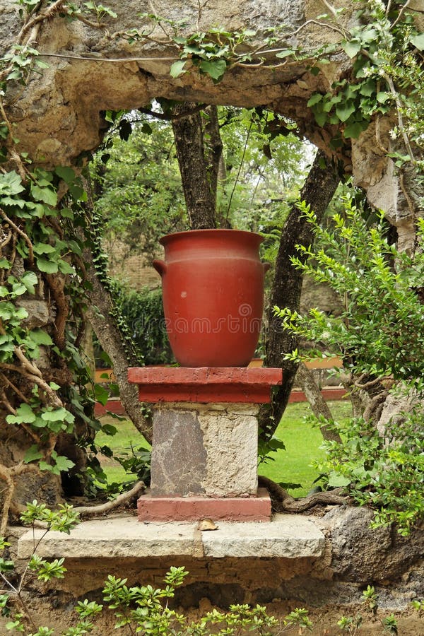 A red ceramic vase over a pole and under a tree branch in the gardens of an hacienda in Guanajuato, mexican colonial heartland. A red ceramic vase over a pole and under a tree branch in the gardens of an hacienda in Guanajuato, mexican colonial heartland.