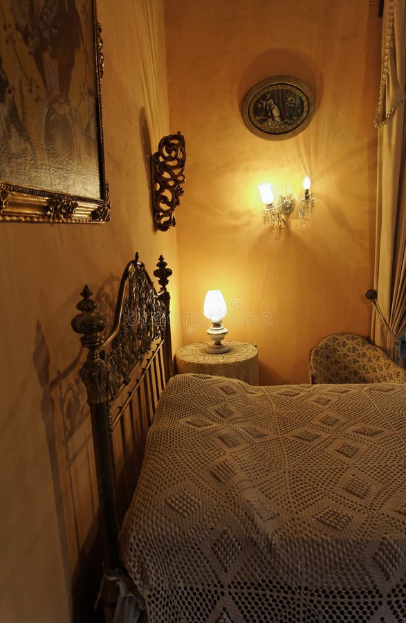 A typical quiet hacienda farm house room, the bed some lighting and two paintings hanging on the yellow walls. City of Guanajuato, mexican colonial heartland, Mexico. A typical quiet hacienda farm house room, the bed some lighting and two paintings hanging on the yellow walls. City of Guanajuato, mexican colonial heartland, Mexico.