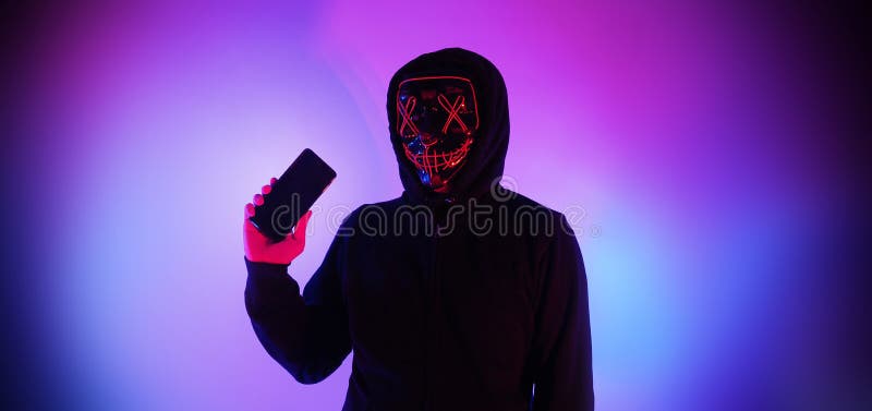 Anonymous hacker and face mask with smartphone in hand. Man in black hood shirt trying to hack personal data from mobile phone. Represent cyber crime data hacking or personal data stealing concept. Anonymous hacker and face mask with smartphone in hand. Man in black hood shirt trying to hack personal data from mobile phone. Represent cyber crime data hacking or personal data stealing concept