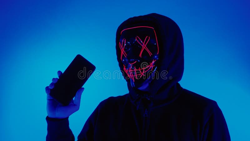 Anonymous hacker and face mask with smartphone in hand. Man in black hood shirt trying to hack personal data from mobile phone. Represent cyber crime data hacking or personal data stealing concept. Anonymous hacker and face mask with smartphone in hand. Man in black hood shirt trying to hack personal data from mobile phone. Represent cyber crime data hacking or personal data stealing concept