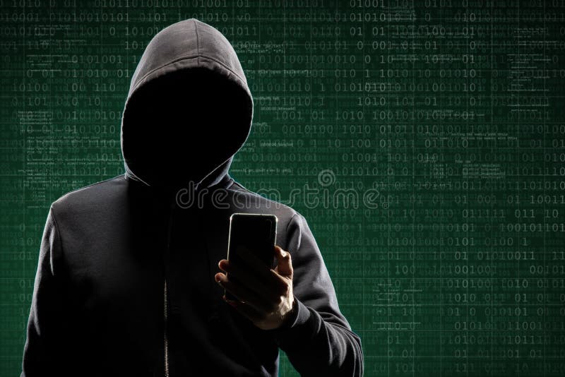 Anonymous computer hacker with a smartphone over abstract digital background. Obscured dark face in mask and hood. Data thief, internet attack, darknet fraud, dangerous viruses and cyber security concept. Anonymous computer hacker with a smartphone over abstract digital background. Obscured dark face in mask and hood. Data thief, internet attack, darknet fraud, dangerous viruses and cyber security concept.