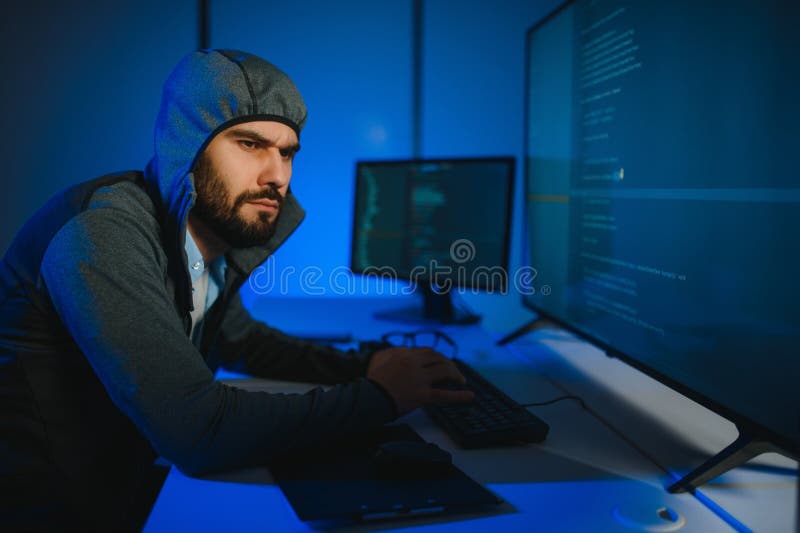 Hacker with computer, man sitting at a table in a hoody royalty free stock photo