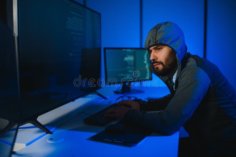 Hacker with computer, man sitting at a table in a hoody royalty free stock images