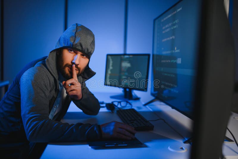 Hacker with computer, man sitting at a table in a hoody stock photo