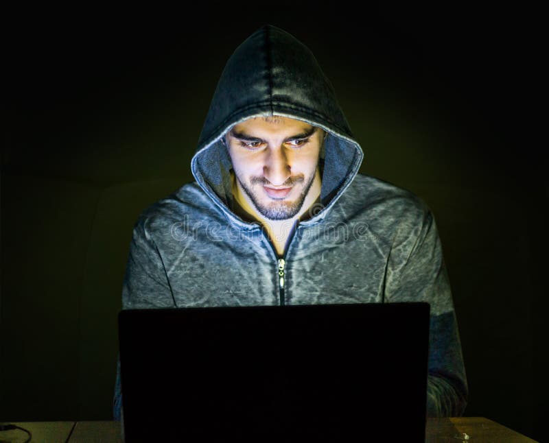 Hacker trying to scam people online - smiling guy on his computer browsing the internet. Hacker trying to scam people online - smiling guy on his computer browsing the internet