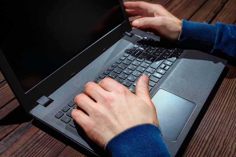 A Hacker with laptop sits at a table and abstract binary code. Business life threat virtual programs