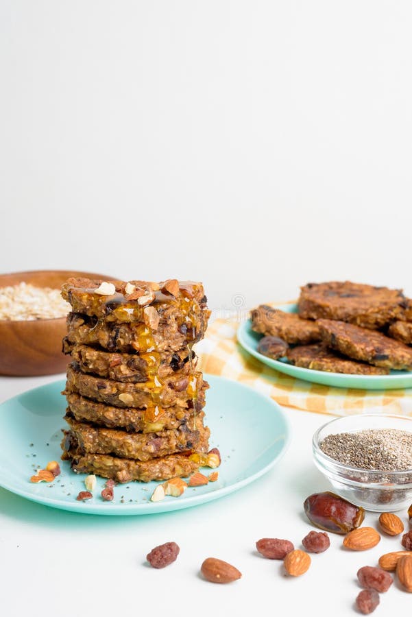 Hafermehlbananenpfannkuchen mit chia Samen-Mandelpflaumen und Daten gegossen mit Honig und wehgetan Schalenfrüchten auf einem hell lizenzfreie stockbilder