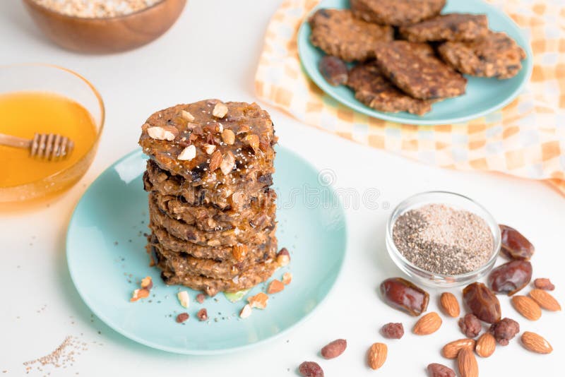 Hafermehlbananenpfannkuchen mit chia Samen-Mandelpflaumen und Daten gegossen mit Honig und wehgetan Schalenfrüchten auf einem hell lizenzfreies stockfoto