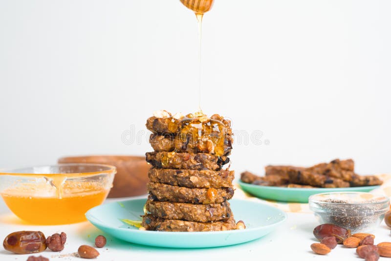 Hafermehlbananenpfannkuchen mit chia Samen-Mandelpflaumen und Daten gegossen mit Honig und wehgetan Schalenfrüchten auf einem hell stockfoto