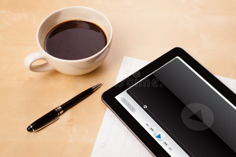 Haga tabletas la PC que muestra al reproductor multimedia en la pantalla con una taza de café encendido imágenes de archivo libres de regalías