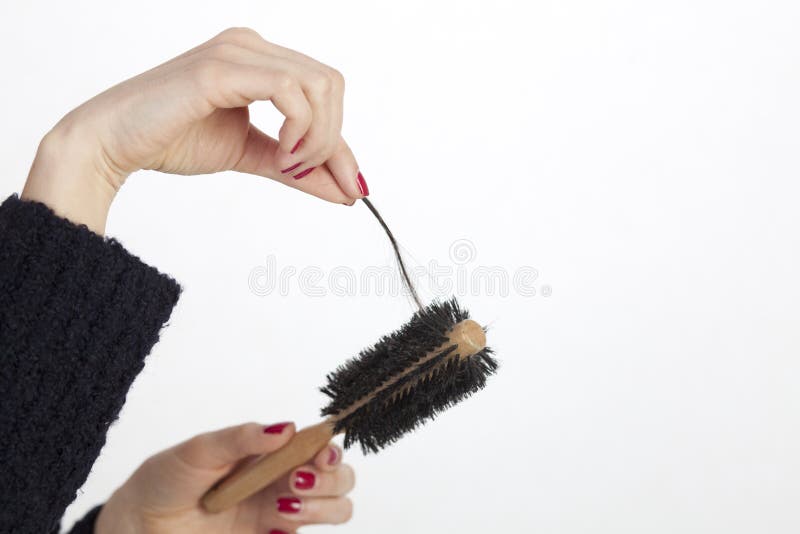 Woman checking her hairbrush for lost hair. Woman checking her hairbrush for lost hair