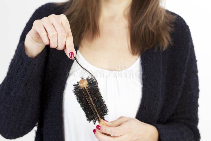 Woman checking her hairbrush for lost hair. Woman checking her hairbrush for lost hair