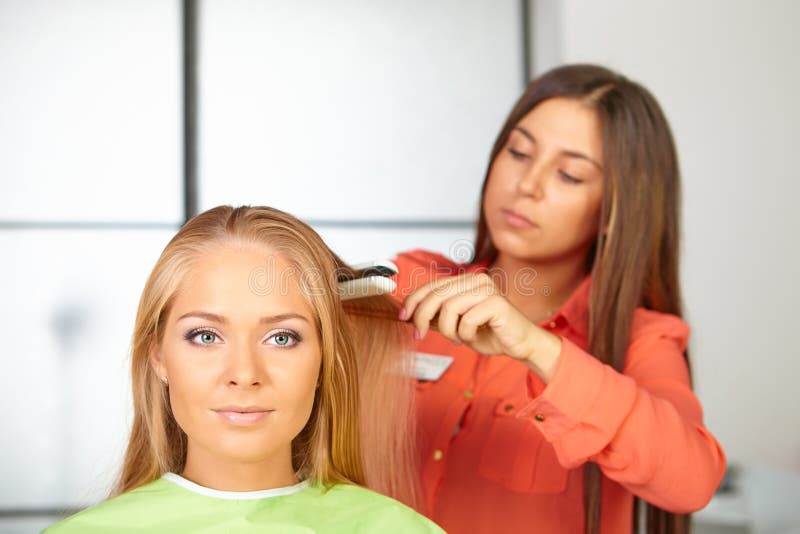 Hair salon. Womens haircut. Use of straightener.