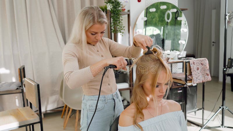 Hairdresser with a curling iron making hair style.