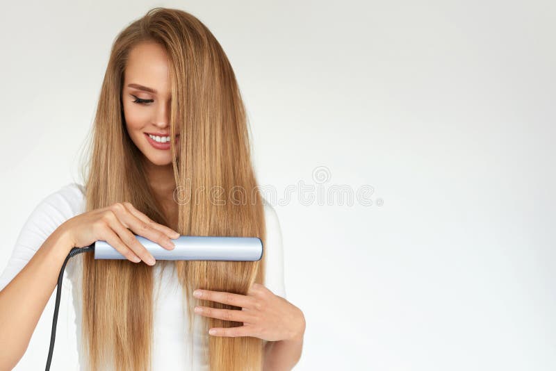 Hairdressing. Woman With Beautiful Long Hair Using Straightener