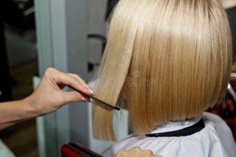 Hairstyle. Attractive Blonde with Short Hair Does a Hairstyle with an  Electric Iron. Hair Straightener Gray Background. Close-up Stock Image -  Image of adult, hands: 170194817
