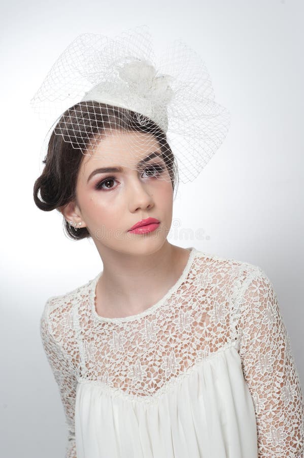 Hairstyle and make up - beautiful young girl art portrait. Cute brunette with white cap and veil, studio shot. Attractive girl