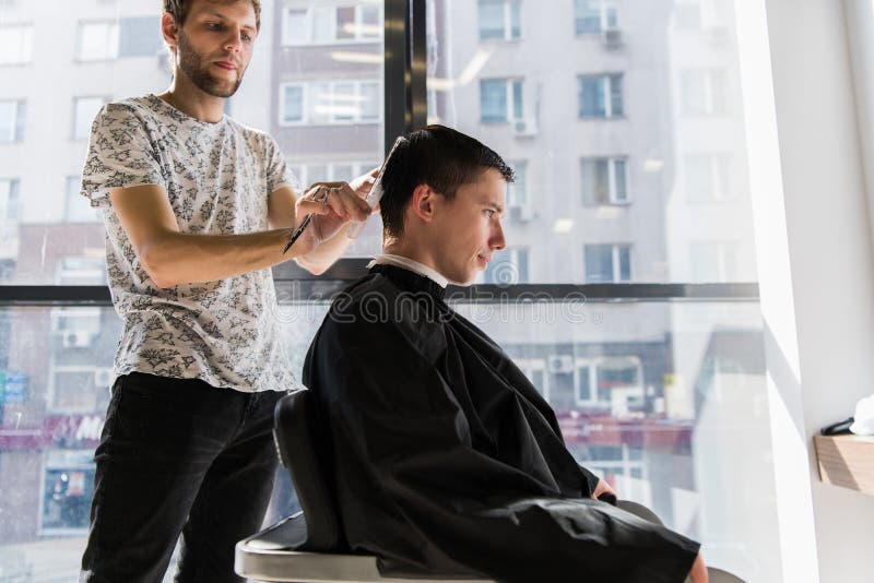 Hairstyling del ` s degli uomini e haircutting in un negozio di barbiere o in un salone di capelli fotografia stock Hairstyling del ` s degli uomini e haircutting in un negozio di barbiere o in un salone di capelli fotografia stock