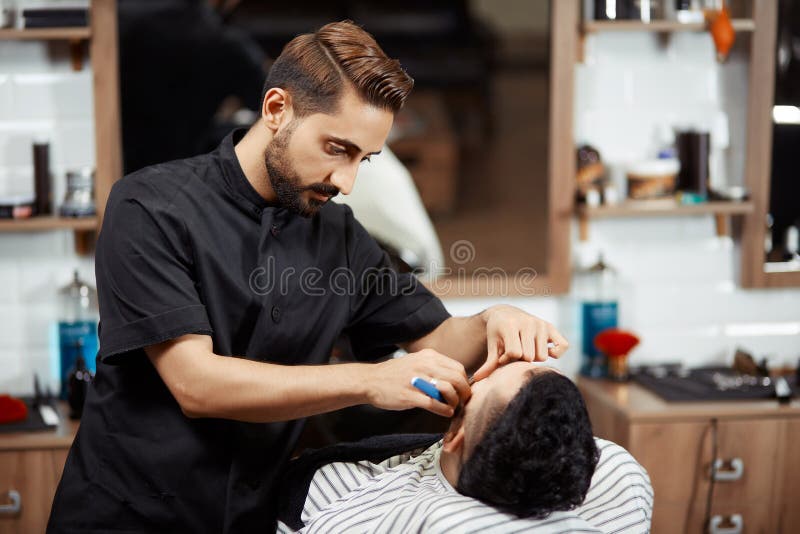 Hairstylist tnący chleb klient w nowożytnym fryzjerze męskim zdjęcie stock Hairstylist tnący chleb klient w nowożytnym fryzjerze męskim zdjęcie stock
