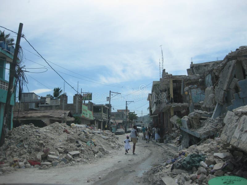 Describes the image immediately after the earthquake in haiti, people coming out of the houses destroyed, still confused on the street, in the background stands a little girl dressed in white. Describes the image immediately after the earthquake in haiti, people coming out of the houses destroyed, still confused on the street, in the background stands a little girl dressed in white.