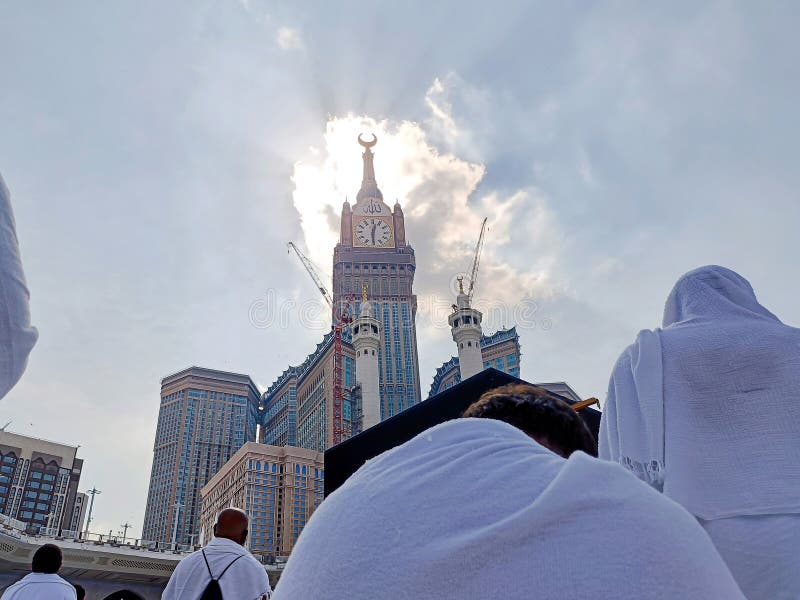 Hajj lub umrah pilgrims czekający na modlitwę przed kaabą z wieżą zegarową w obraz stock