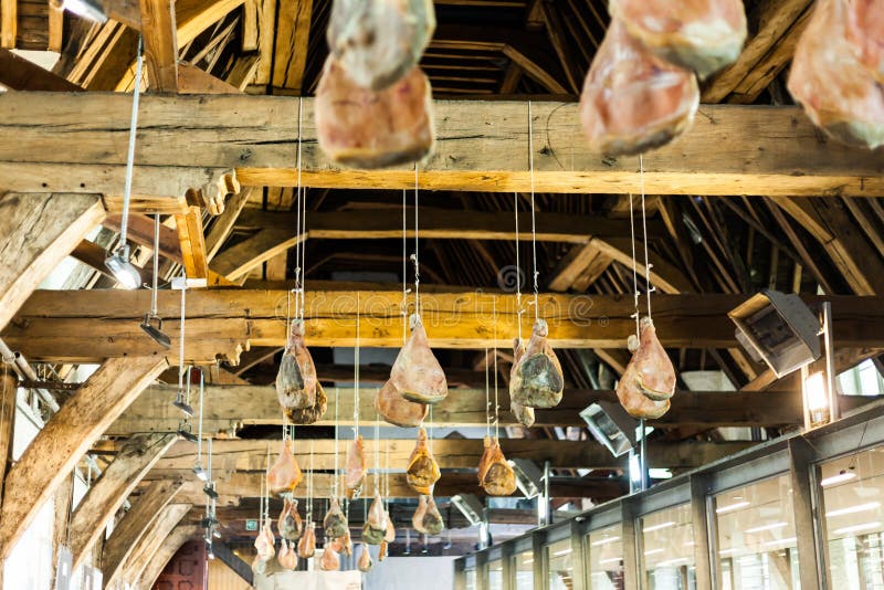 Hakad skinka på trästrålar som hänger från taket Traditionell väg av att torka kött Grisköttskinka som torkar på luften royaltyfri bild Hakad skinka på trästrålar som hänger från taket Traditionell väg av att torka kött Grisköttskinka som torkar på luften royaltyfri bild