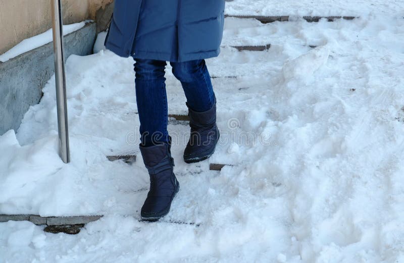 Hal trappa Closeupkvinnas ben i en blått ner omslaget som går ner en snöig trappuppgång royaltyfria bilder