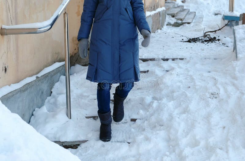 Hal trappa Den oigenkännliga kvinnan i en blått klår upp ner att gå ner en snöig trappuppgång royaltyfria foton