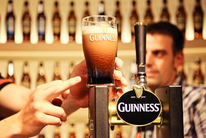 Halbes Liter von Guinneß auf dem Zähler an der Guinness-Lagerhaus-Brauerei mit dem Fingerzeigen und Person auf den Hintergrund stockbilder Halbes Liter von Guinneß auf dem Zähler an der Guinness-Lagerhaus-Brauerei mit dem Fingerzeigen und Person auf den Hintergrund stockbilder