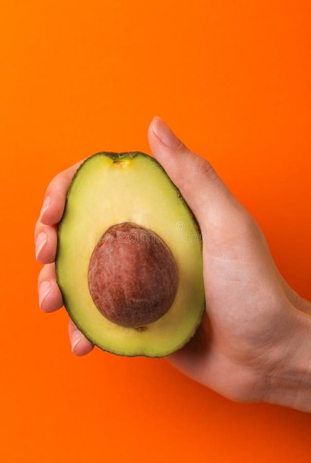 Half of avocado with kernel in female hand stock photography