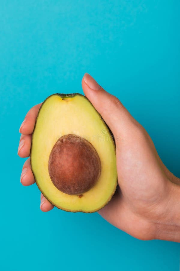 Half of avocado with kernel in female hand royalty free stock image