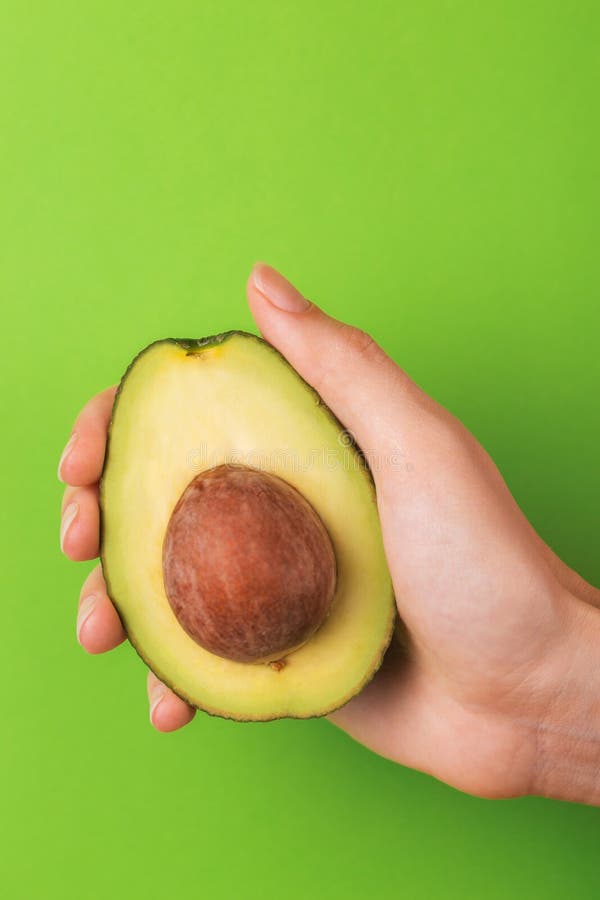 Half of avocado with kernel in female hand royalty free stock images