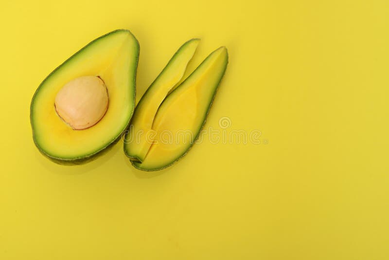Half avocado and slice on a yellow background stock image