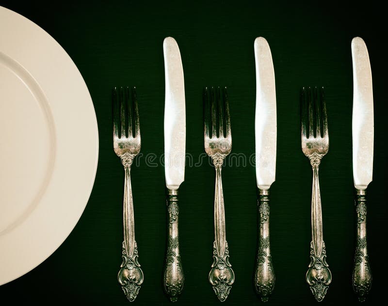 Half of an Empty White Plate with a Fork and a Knife on a Brown Stock