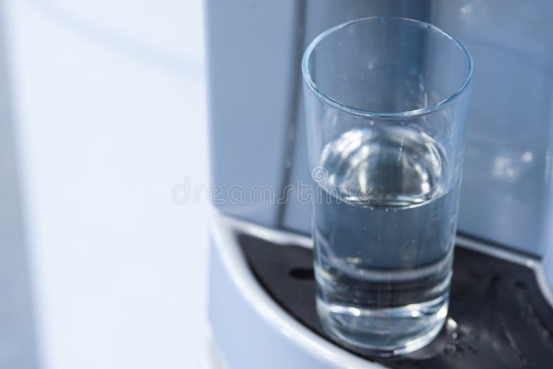 Half full glass in water dispenser stock image