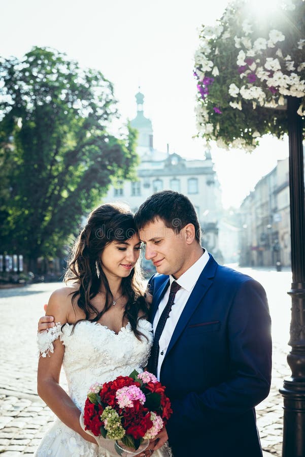 Half-length outdoor portrait of the adorable stylish wedding couple softly hugging, standing head-to-head and holding royalty free stock images Half-length outdoor portrait of the adorable stylish wedding couple softly hugging, standing head-to-head and holding royalty free stock images