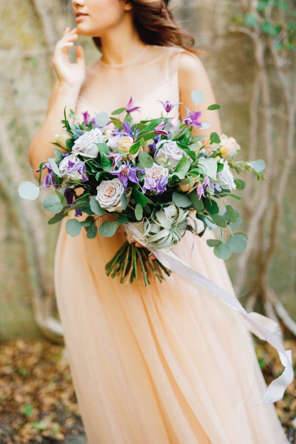 Half-portrait of a bride in a beige dress and a beautiful bouquet of roses in her hands