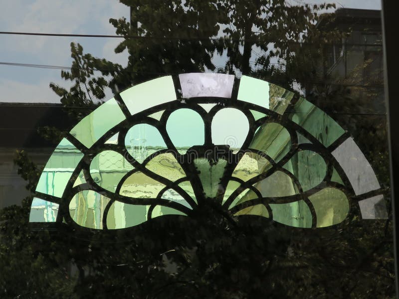 Half Round Window Above a Door Reflecting a Tree at the Other Side of
