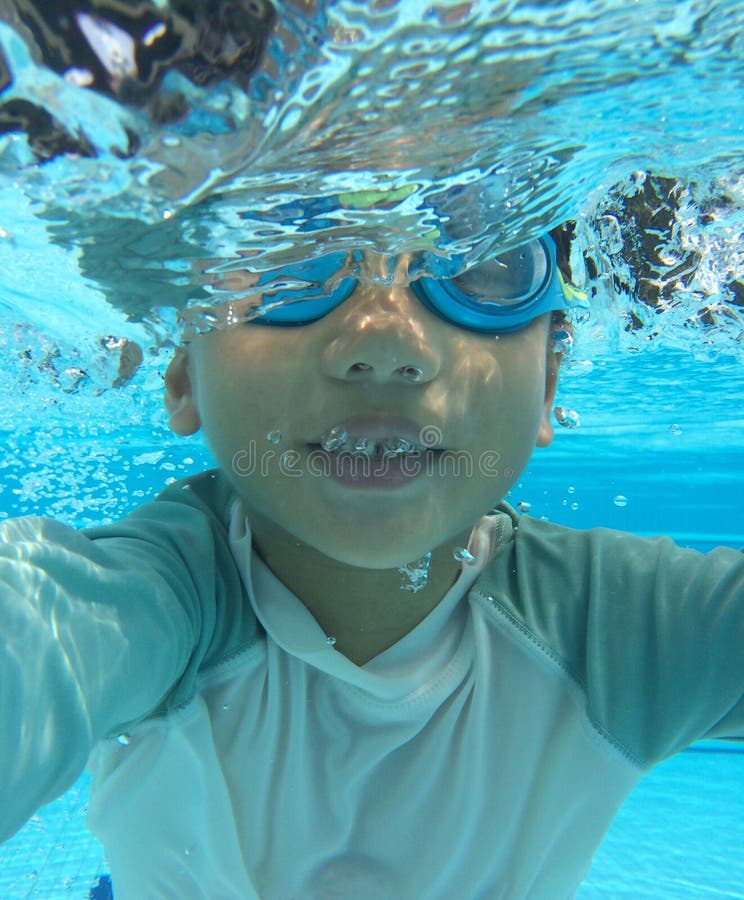 Half submerged 4 year old asian boy playing in pool