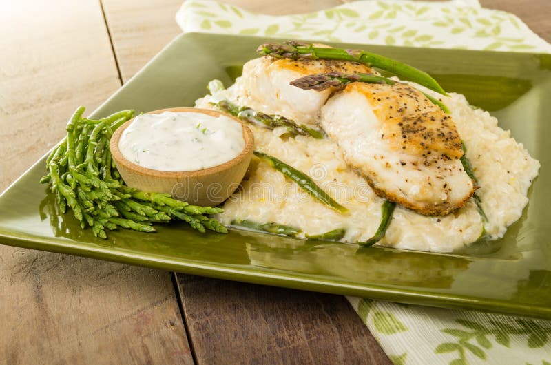Halibut with asparagus risotto on green plate stock photos
