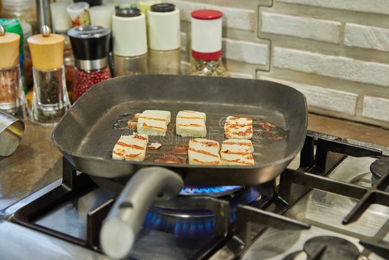 Halloumi Cheese is Fried on Ribbed Pan Over Fire on Gas Stove Stock
